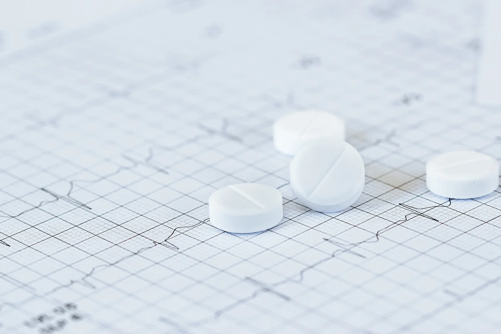 White tablets resting on a printed ECG tracing