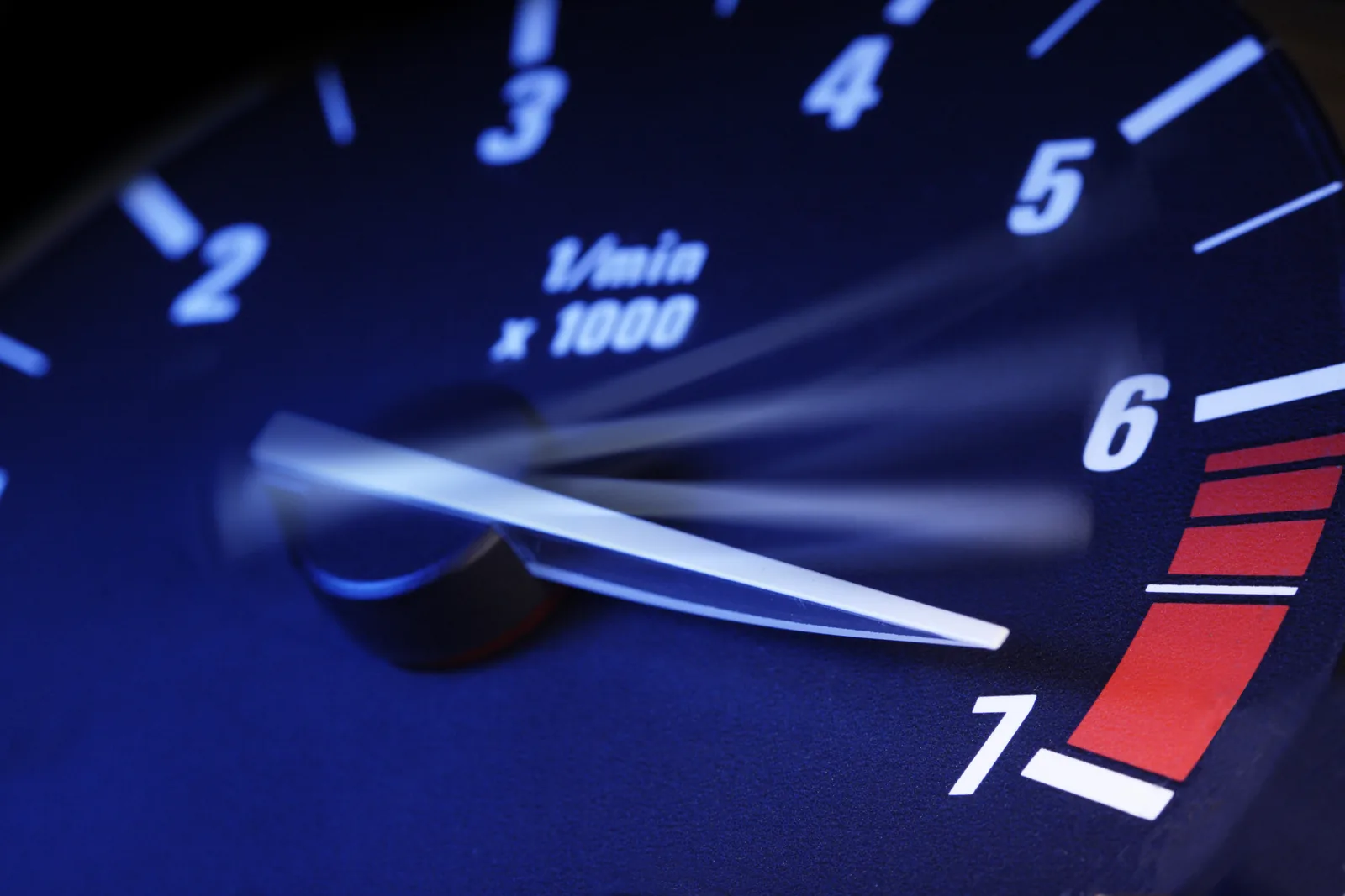 A car tachometer with the needle rising toward the red line